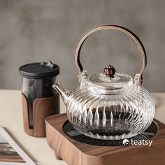 a glass tea pot sitting on top of a wooden tray