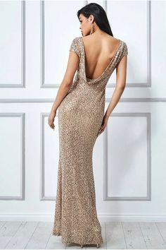 the back of a woman in a gold dress standing against a wall with her hands on her hips