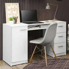 a white desk with a laptop on top of it next to a chair and clock