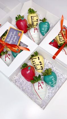 four decorated strawberries in boxes with writing on them