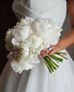 a bride holding a bouquet of white flowers