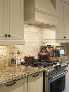 a stove top oven sitting inside of a kitchen next to white cabinets and counter tops