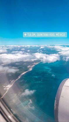 an airplane wing flying over the ocean and clouds