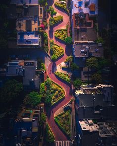 an aerial view of a winding road in the middle of a city with buildings and trees on both sides