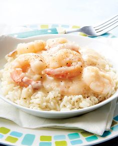 a white bowl filled with shrimp and rice on top of a blue and green plate