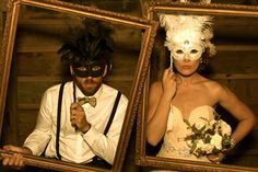 a man and woman wearing masks standing next to each other in front of wooden frames