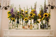 sunflowers and liquor bottles are arranged on a mantel