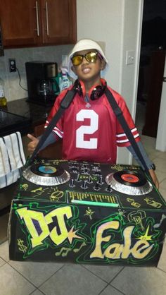 a young boy in a football jersey holding a dj's tape box with the number 2 on it