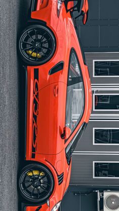 an orange sports car parked in front of a garage