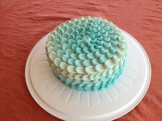 a blue and white cake sitting on top of a white plate next to a red tablecloth