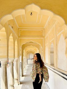 a woman is standing in an archway with her hand on her hip and looking off to the side