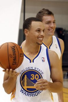 two basketball players are smiling and holding a ball