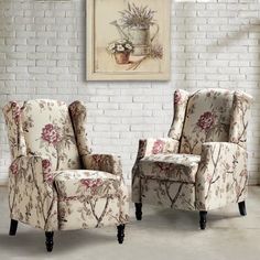 two chairs sitting next to each other in front of a brick wall with flowers on it