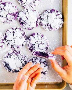 a person scooping powdered sugar onto some cookies