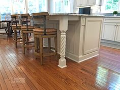 a kitchen island with four stools in the center and an island table on one side