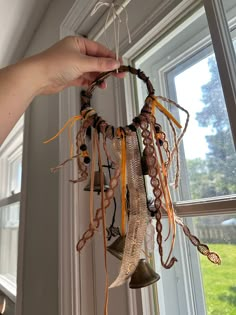 a person holding a bell in front of a window with ribbons hanging from it's sides