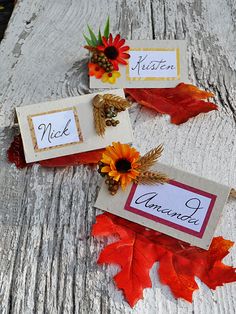 three place cards with autumn leaves and sunflowers sitting on top of each other