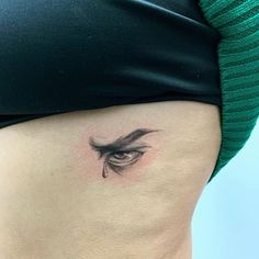 a woman's stomach with a teary eye tattoo on the side of her belly