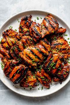 grilled chicken on a white plate topped with chives and seasoning sprinkles