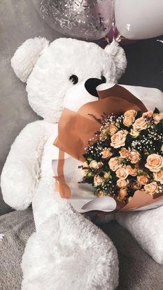 a white teddy bear holding a bouquet of roses