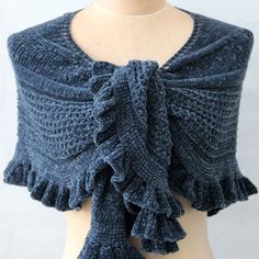 a knitted shawl with ruffles on the front and back, sitting on top of a mannequin