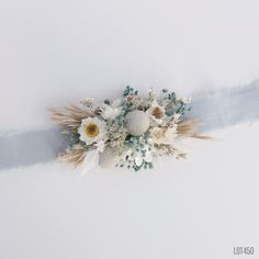 an arrangement of flowers and grass on a white background with blue ribbon in the center