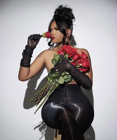 a woman sitting on a stool with roses in her lap and black latex gloves