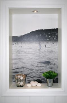 an image of boats on the water through a window sill with rocks and a potted plant