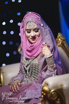 a woman in a purple hijab sits on a chair with her hands clasped