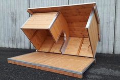 an open wooden box sitting on top of a black floor next to a metal wall