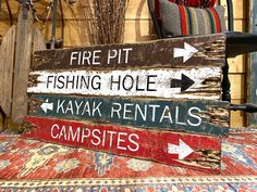 a wooden sign that says fire pit, fishing hole, kayak rentals and campsites