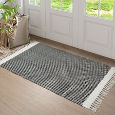 a black and white area rug with fringes on the floor next to a door