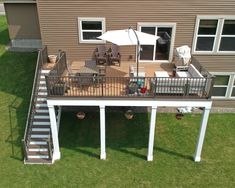 an overhead view of a deck with chairs and umbrella on the grass next to a house