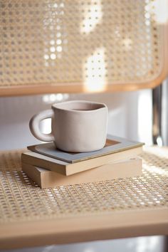 a white cup sitting on top of a stack of books next to a wooden bench