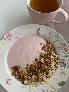 a plate with granola and yogurt next to a cup of tea