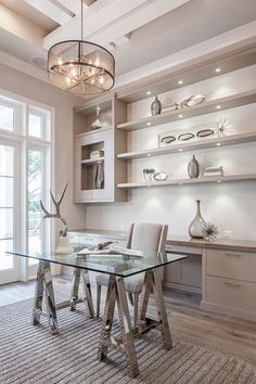 a glass dining table in a room with white walls and flooring, along with built - in shelving