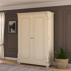 a white armoire in a living room next to a potted plant