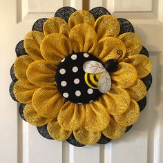 a yellow and black mesh wreath with a bee on it's front door handle