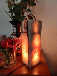 two vases with flowers in them sitting on a table next to a flower pot