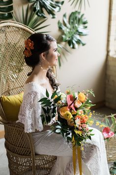 a woman sitting in a wicker chair holding a bouquet of yellow and pink flowers