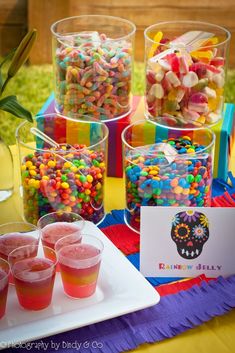 there are many cups with candy in them on the table next to each other,