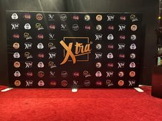 the xtra logo is displayed on a red carpet in front of a black backdrop