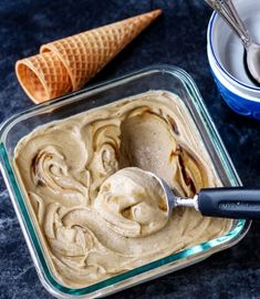 an ice cream in a glass dish with a spoon next to it on a table