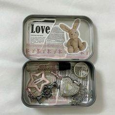 an open tin box with key chains and other items in it