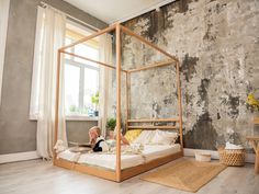 a child is laying on a bed in a room with concrete walls and wood flooring