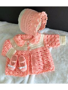 a crocheted baby outfit and booties on a bed