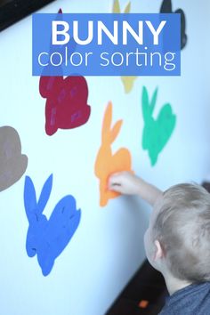 a young boy is painting on the wall with colored paper and bunny silhouettes in different colors