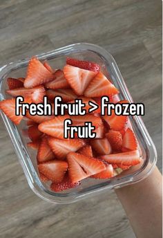 someone is holding up a plastic container with strawberries in it and the words fresh fruit = frozen fruit