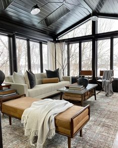 a living room filled with lots of furniture next to large windows and a rug on the floor