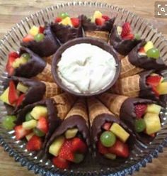 a glass plate topped with fruit and chocolate covered pastries on top of a wooden table